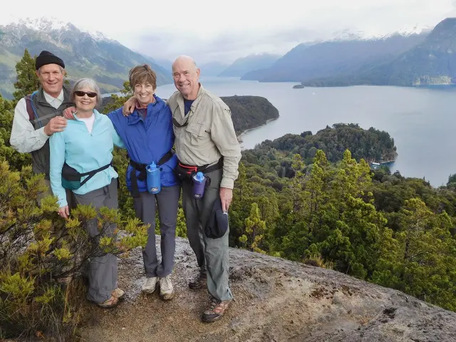 Four guests at a mountain lookout above a lake.